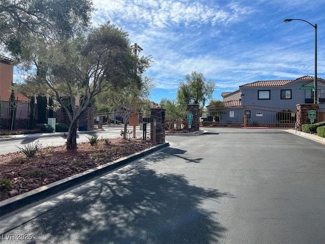 view of street featuring a gated entry, curbs, street lights, and a gate