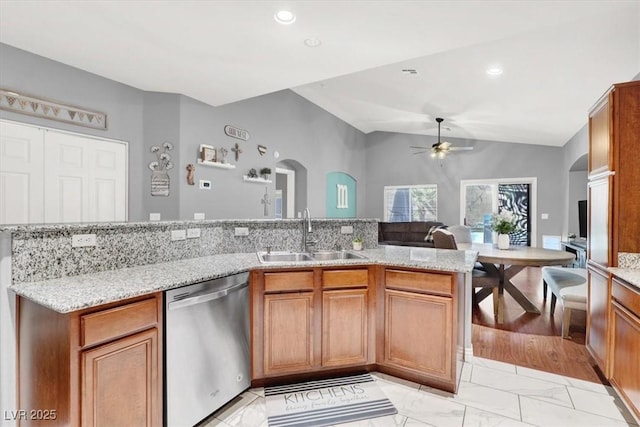 kitchen featuring dishwasher, brown cabinetry, arched walkways, and a sink