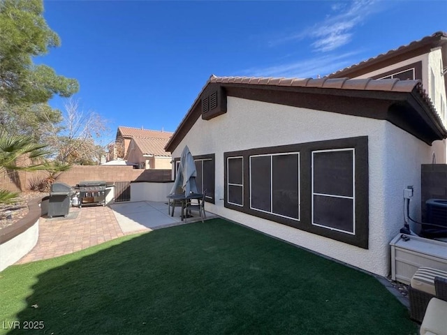 back of property featuring a yard, stucco siding, a patio, and fence