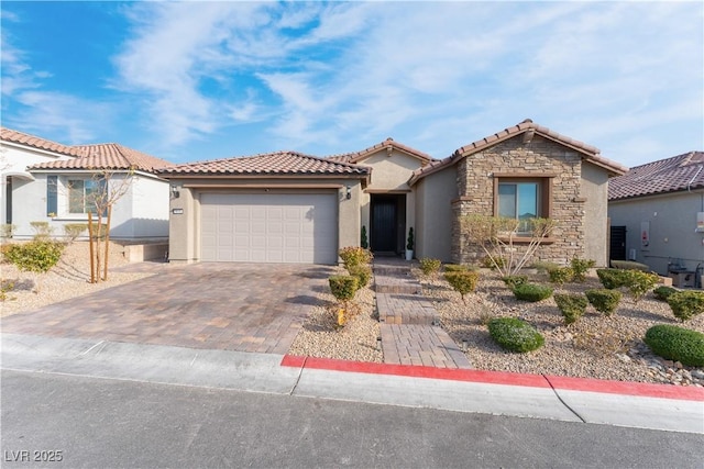 mediterranean / spanish house featuring stucco siding, decorative driveway, stone siding, a garage, and a tiled roof