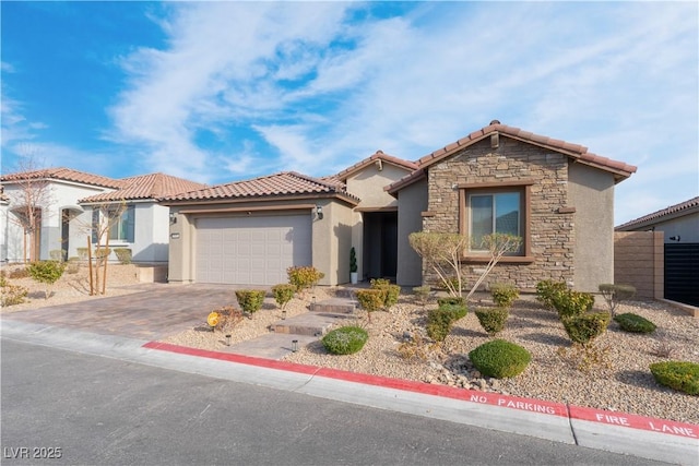 mediterranean / spanish home with stucco siding, driveway, a tile roof, stone siding, and a garage