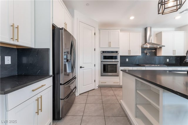 kitchen featuring light tile patterned floors, dark countertops, appliances with stainless steel finishes, and wall chimney exhaust hood