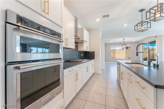 kitchen featuring visible vents, a sink, dark countertops, backsplash, and stainless steel appliances