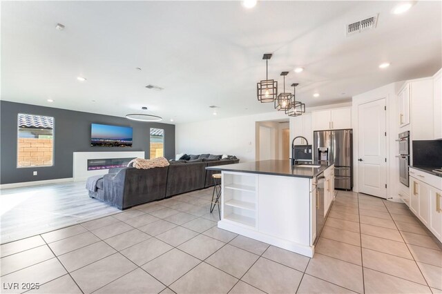 kitchen with visible vents, light tile patterned flooring, a sink, appliances with stainless steel finishes, and dark countertops