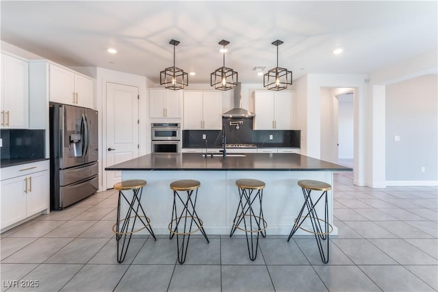 kitchen with a sink, stainless steel appliances, dark countertops, and wall chimney exhaust hood