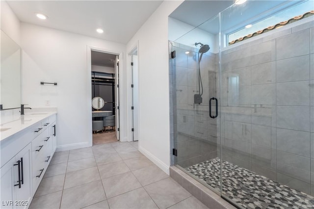 full bathroom featuring double vanity, a sink, tile patterned flooring, a shower stall, and a spacious closet