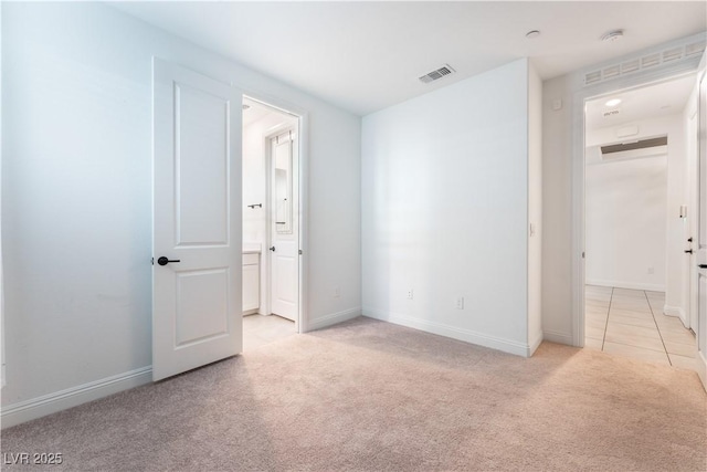 unfurnished bedroom with light tile patterned floors, visible vents, baseboards, and light colored carpet