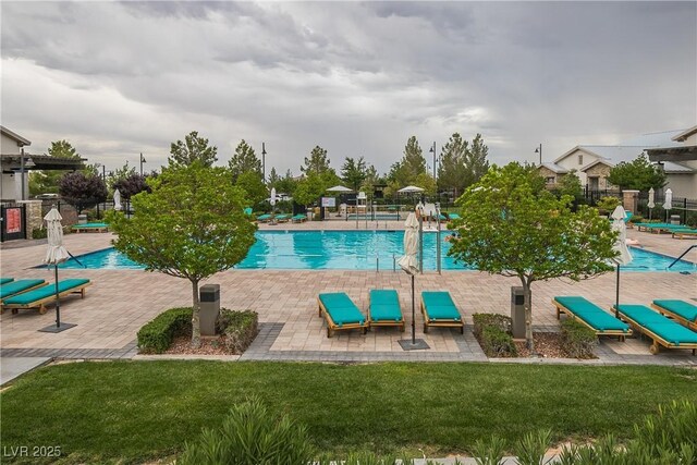 community pool featuring a lawn, a patio, and fence