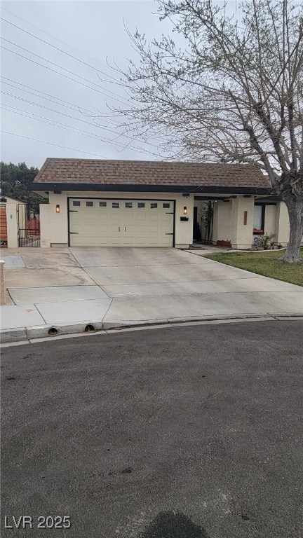 view of front of home featuring concrete driveway, stucco siding, an attached garage, and a shingled roof