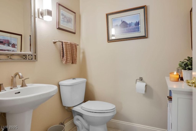 half bath featuring a sink, baseboards, and toilet