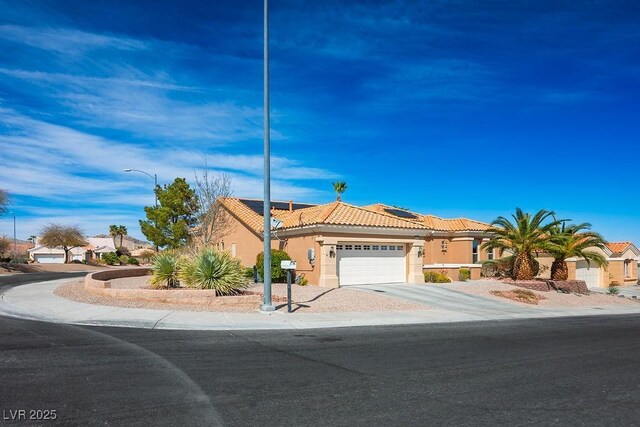 view of front of property with solar panels, a tiled roof, concrete driveway, stucco siding, and an attached garage