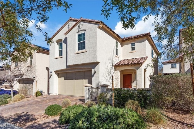 mediterranean / spanish-style home with stucco siding, an attached garage, a tile roof, and decorative driveway