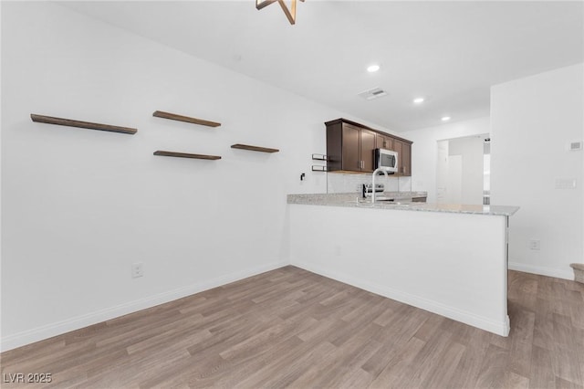 12367 Indigo Montage Rd Unit 3, Las Vegas, NV 89183 - kitchen featuring stainless steel microwave, light wood-style flooring, dark brown cabinetry, baseboards, and recessed lighting