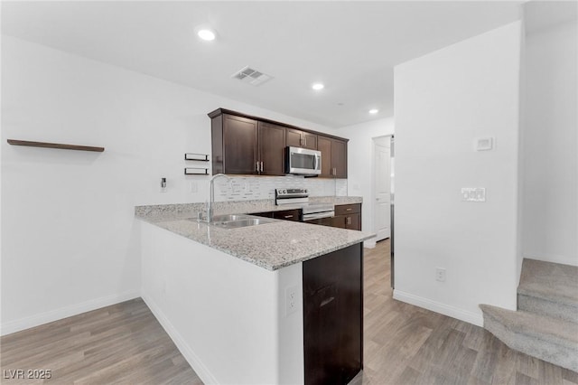 12367 Indigo Montage Rd Unit 3, Las Vegas, NV 89183 - kitchen with appliances with stainless steel finishes, a sink, dark brown cabinetry, light wood finished floors, and baseboards