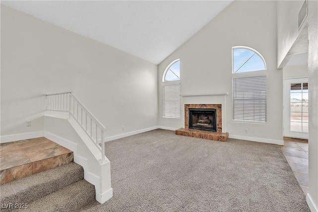 unfurnished living room featuring high vaulted ceiling, carpet floors, plenty of natural light, and a fireplace