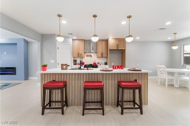 kitchen with decorative light fixtures, decorative backsplash, an island with sink, and light countertops