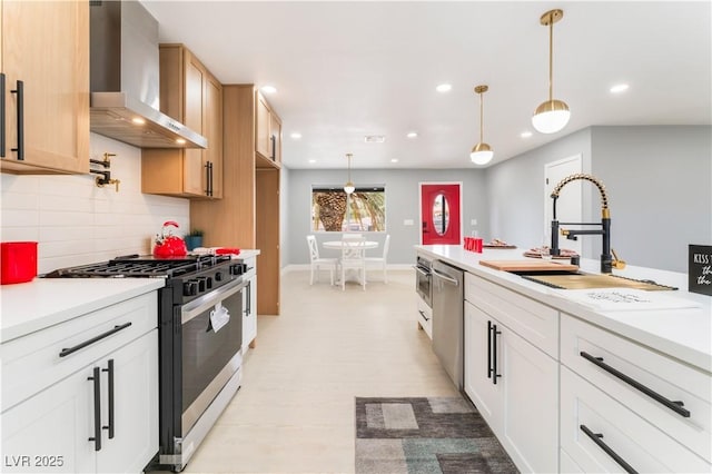 kitchen with a sink, decorative backsplash, light countertops, gas range oven, and wall chimney range hood