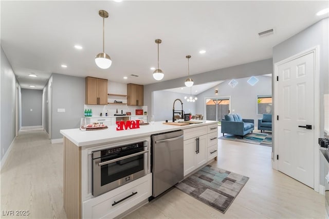 kitchen featuring visible vents, open floor plan, light countertops, stainless steel appliances, and a sink