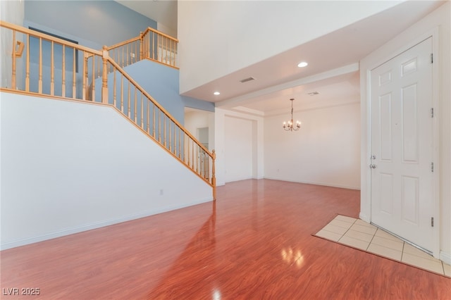 foyer with baseboards, an inviting chandelier, wood finished floors, and stairs