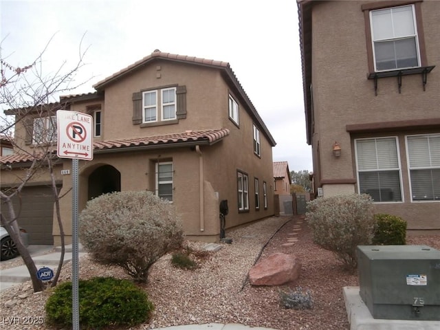 view of side of home featuring a tile roof and stucco siding