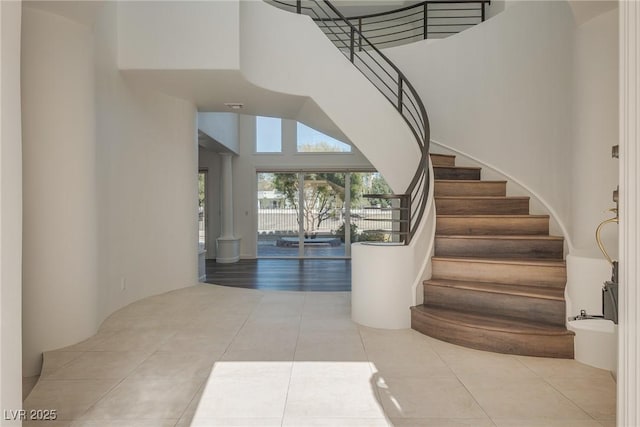 stairway featuring tile patterned floors and a high ceiling