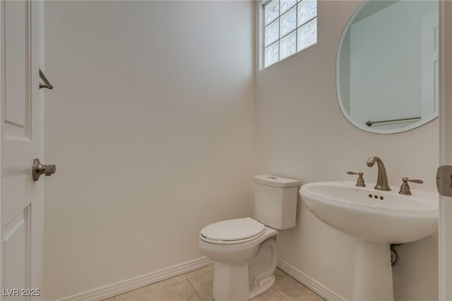 bathroom with tile patterned flooring, toilet, baseboards, and a sink