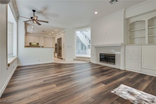 unfurnished living room featuring visible vents, built in features, stairs, a tile fireplace, and wood finished floors