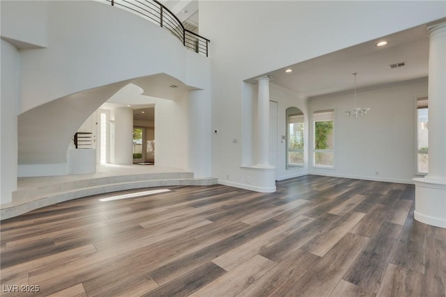 interior space with visible vents, wood finished floors, baseboards, and decorative columns