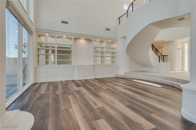 spare room with visible vents, wood finished floors, arched walkways, a high ceiling, and stairs