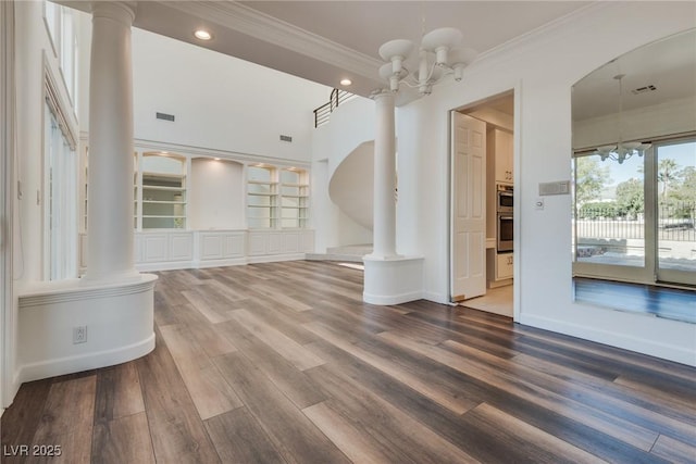 empty room with wood finished floors, visible vents, an inviting chandelier, decorative columns, and ornamental molding