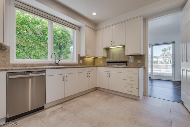 kitchen featuring stainless steel dishwasher, decorative backsplash, light tile patterned flooring, and a healthy amount of sunlight