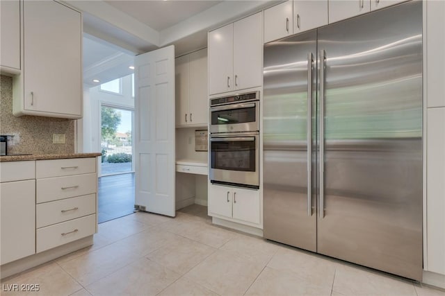 kitchen with white cabinetry, light tile patterned flooring, backsplash, and stainless steel appliances