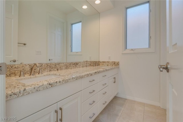 bathroom featuring baseboards, double vanity, recessed lighting, a sink, and tile patterned flooring