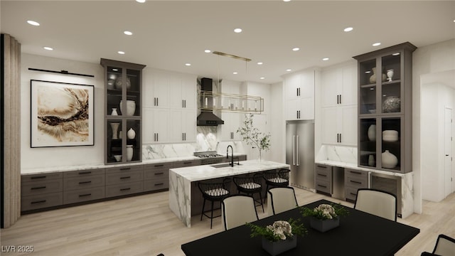 kitchen with stainless steel appliances, glass insert cabinets, tasteful backsplash, a center island with sink, and wall chimney exhaust hood