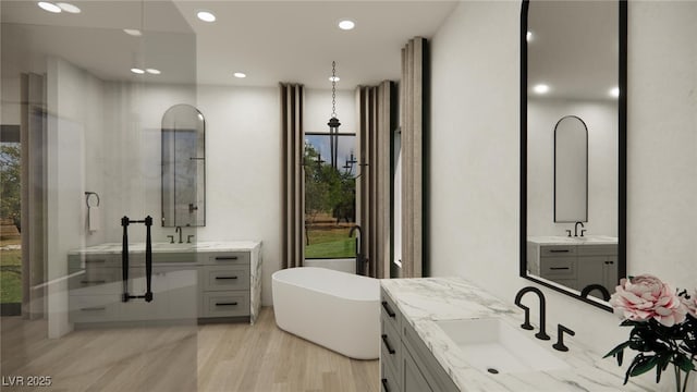 bathroom featuring two vanities, wood finished floors, and a sink