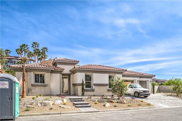 mediterranean / spanish-style home with stucco siding, a tile roof, driveway, and an attached garage