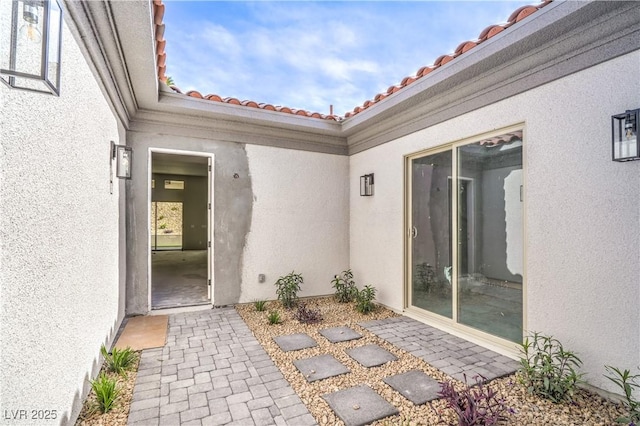 property entrance with a patio, stucco siding, and a tiled roof