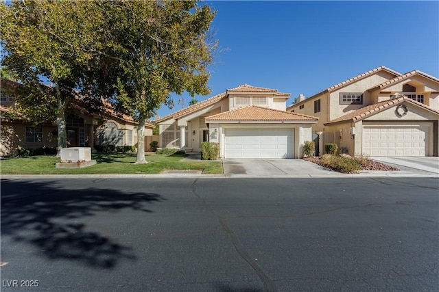 mediterranean / spanish house featuring stucco siding, concrete driveway, a front lawn, a garage, and a tile roof