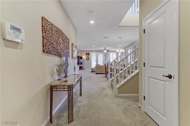 hall with baseboards, an inviting chandelier, recessed lighting, stairs, and light carpet