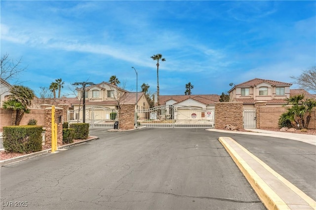 view of road featuring street lighting, a gated entry, a residential view, curbs, and a gate