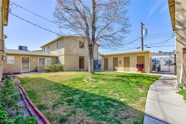 exterior space featuring a front yard, a gate, fence, and stucco siding