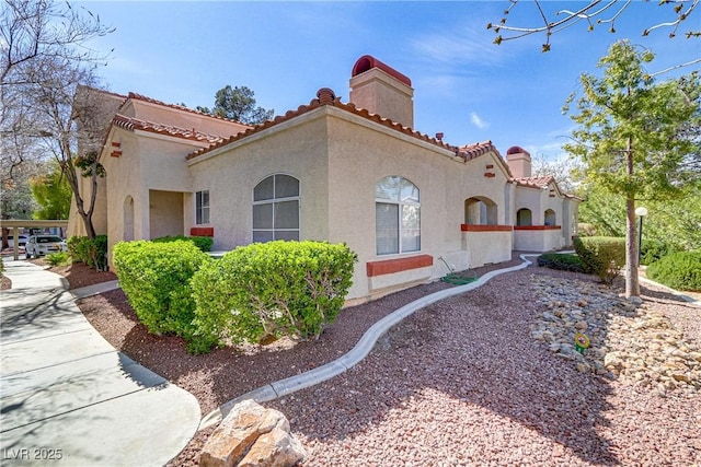 view of side of home featuring a chimney, stucco siding, and a tile roof