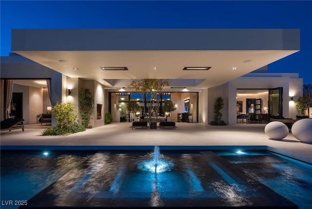 pool at twilight with an outdoor pool and a patio