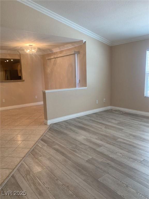 spare room with a notable chandelier, light wood-type flooring, and crown molding