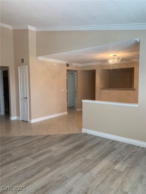 empty room featuring crown molding, wood finished floors, and baseboards