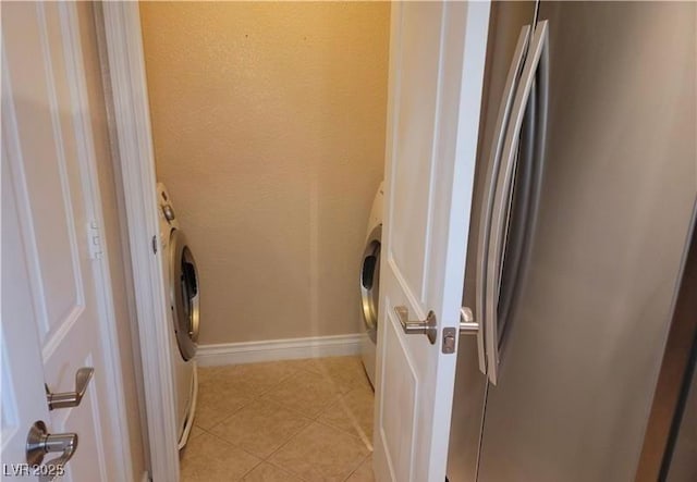 clothes washing area with baseboards, washer / clothes dryer, light tile patterned flooring, and laundry area