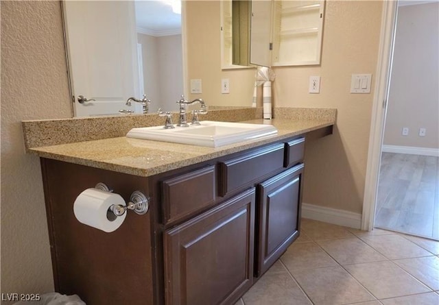 bathroom featuring tile patterned floors, baseboards, vanity, and crown molding