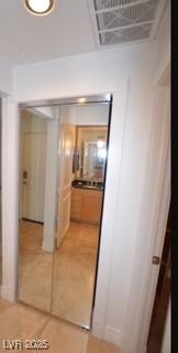 hallway featuring light tile patterned floors and visible vents