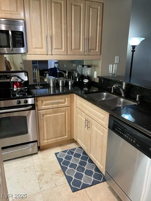 kitchen with dark countertops, light brown cabinetry, light tile patterned floors, stainless steel appliances, and a sink