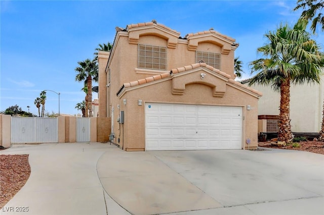 mediterranean / spanish home featuring stucco siding, a gate, concrete driveway, a garage, and a tiled roof